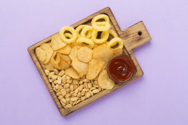 Renkli arka planda lezzetli atıştırmalıklar olan tahta, üst görünüm