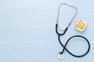 Ahşap arka planda kalp ilaçları olan steteskop.