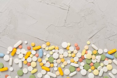 Beton arka planda farklı ilaç ve kapsüller var.