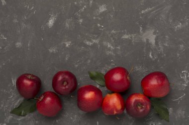 Beton zemin üzerinde yaprakları olan taze kırmızı elmalar, üst görünüm