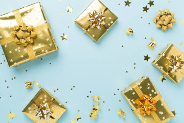 Altın hediye kutuları ve renkli arka planda konfeti, üst görünüm