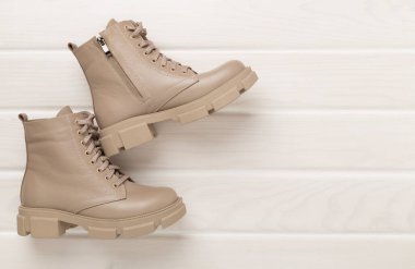 Ahşap arka planda bej renkli moda botlar, üst manzara.