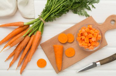 Siyah ahşap arka planda taze havuç ve domatesli kase.