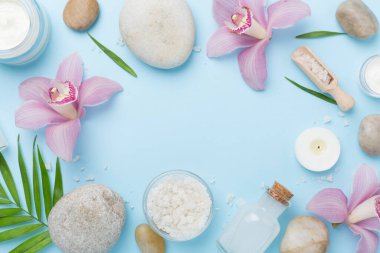 Renkli arkaplanda orkideler ve masaj taşlarıyla kompozisyon, üst görünüm