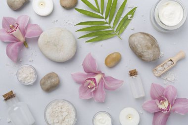Renkli arkaplanda orkideler ve masaj taşlarıyla kompozisyon, üst görünüm