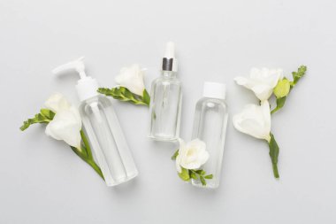 Renk arka planında frezya çiçekleri olan yüz kozmetik ürünleri, üst görünüm