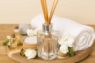 Tahta masa üzerinde frezya çiçeği ve aroma yayıcı içeren spa kompozisyonu
