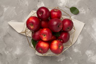 Beton zemin üzerinde yaprakları olan taze kırmızı elmalar, üst görünüm