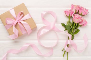 Pembe güller, hediye kutusu ve ahşap arka planda sekiz şeritten oluşan kompozisyon, üst manzara. Kadınlar Günü konsepti