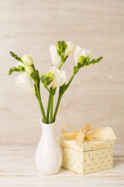 Masanın üzerinde vazoda duran beyaz frezya çiçekleri.