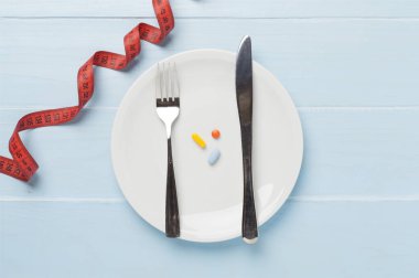 Tahta arka planda boş bir plaka ile mezura, üst, görüş. Kilo verme konsepti