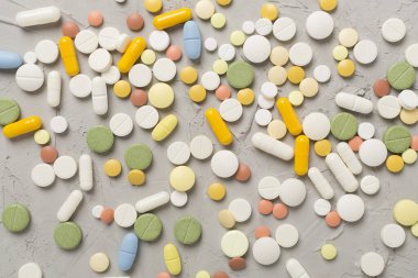 Beton arka planda farklı ilaç ve kapsüller var.