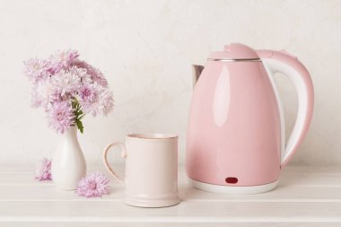 Masada çay ve tatlı ile pembe elektrikli çaydanlık.