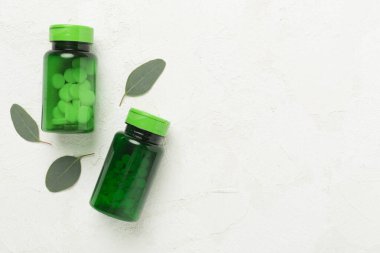 Haplı şişeler ve beton arka planda yeşil yapraklar, üst manzara.