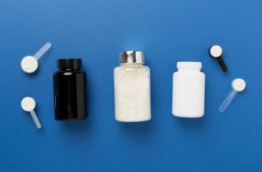 Renkli arka planda protein tozu olan kavanozlar, üst manzara. Spor beslenme konsepti