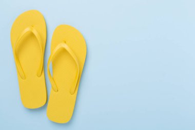 Renkli arka planda parlak sarı parmak arası terlikler, üst manzara. Yaz konsepti