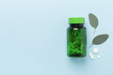 İlaç şişesi ve yeşil yapraklı arka plan, üst görünüm