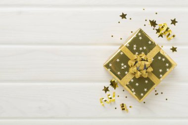 Altın hediye kutuları ve ahşap arka planda konfeti.