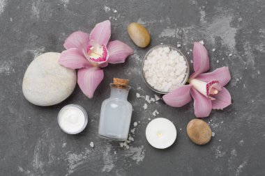 Beton zemin üzerinde orkideler ve masaj taşları olan kompozisyon, üst görünüm