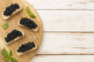 Ahşap arka planda servis edilen siyah havyarlı ekmek dilimi.