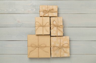 Noel ağacı şeklinde hediye kutuları ahşap arka planda, üst manzara