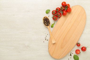 Taze domates, fesleğen, deniz tuzu ve ahşap arka planda kesim tahtası olan baharatlar.