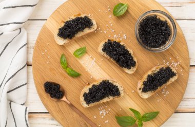 Ahşap arka planda servis edilen siyah havyarlı ekmek dilimi.