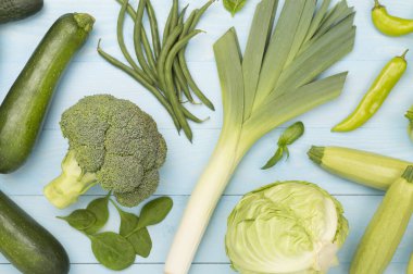 Ahşap arka planda farklı yeşil sebzeler.