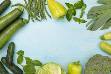 Ahşap arka planda farklı yeşil sebzeler.