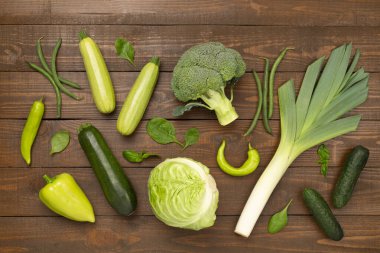 Ahşap arka planda farklı yeşil sebzeler.