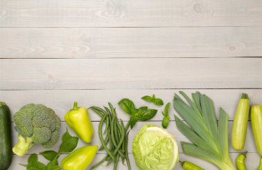 Ahşap arka planda farklı yeşil sebzeler.