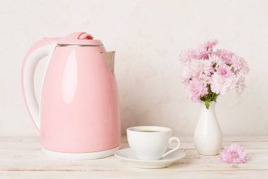 Masada çay ve tatlı ile pembe elektrikli çaydanlık.