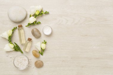 Tahta arka planda kaplıca ürünleri ve çiçeklerle yatıyordu