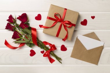 Ahşap arka planda hediye kutusu olan kırmızı gül çiçekleri, üst, manzara. Sevgililer Günü konsepti