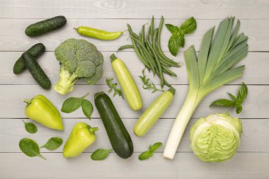 Ahşap arka planda farklı yeşil sebzeler.