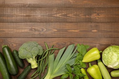 Ahşap arka planda farklı yeşil sebzeler.