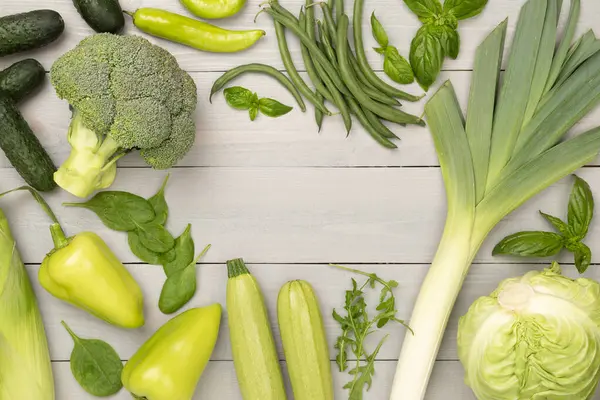 Ahşap arka planda farklı yeşil sebzeler.