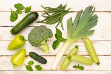 Ahşap arka planda farklı yeşil sebzeler.