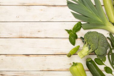 Ahşap arka planda farklı yeşil sebzeler.