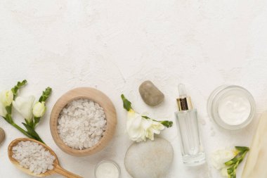 Beton zemin üzerinde spa ürünleri ve çiçeklerle yatıyordu