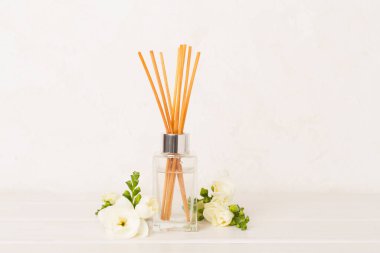 Tahta masa üzerinde frezya çiçeği ve aroma yayıcı içeren spa kompozisyonu