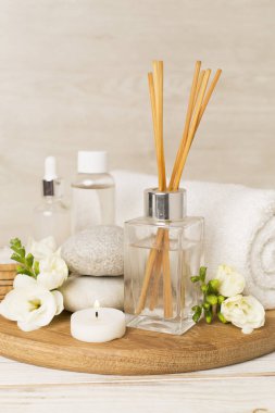 Tahta masa üzerinde frezya çiçeği ve aroma yayıcı içeren spa kompozisyonu