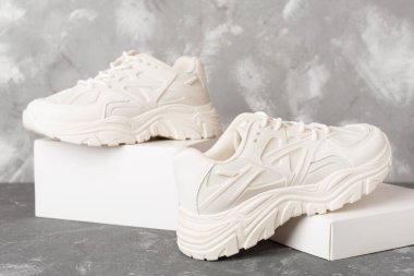 Beton arka planda beyaz kadın spor ayakkabıları