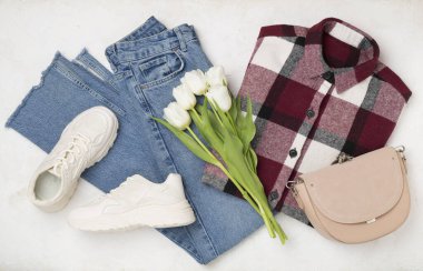 Havalı bahar kıyafetleri ve çimento arkaplanda çiçeklerle yatıyordu