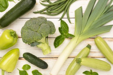 Ahşap arka planda farklı yeşil sebzeler.