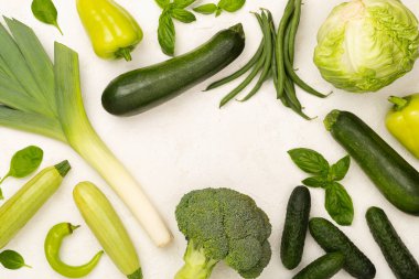 Beton arka planda farklı yeşil sebzeler, üst manzara.