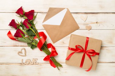 Ahşap arka planda hediye kutusu olan kırmızı gül çiçekleri, üst, manzara. Sevgililer Günü konsepti