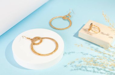 Arkaplanda dekoru olan altın küpeler