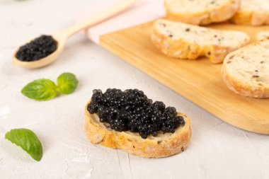 Tahta masada servis edilen siyah havyarlı ekmek dilimi.