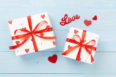 Ahşap zemin üzerinde kırmızı kalpler olan hediye kutuları, üst görünüm